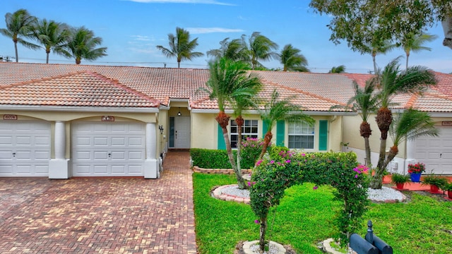 view of front of home featuring an attached garage, a tile roof, decorative driveway, and stucco siding