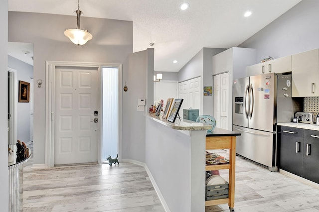 entryway featuring light wood-style floors, baseboards, vaulted ceiling, and recessed lighting