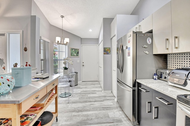 kitchen with light wood finished floors, tasteful backsplash, an inviting chandelier, a textured ceiling, and pendant lighting