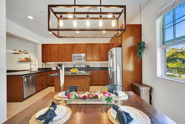 kitchen with dark countertops, tasteful backsplash, appliances with stainless steel finishes, and a center island