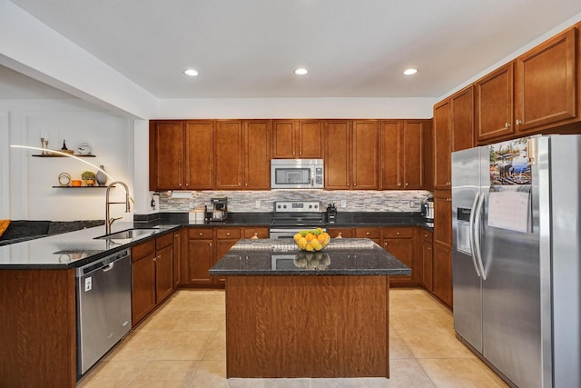 kitchen featuring light tile patterned floors, appliances with stainless steel finishes, a sink, dark stone countertops, and a peninsula