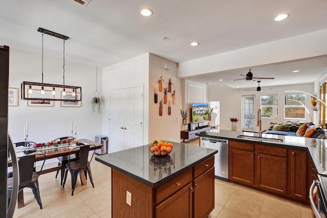 kitchen featuring brown cabinetry, dark stone counters, a center island, stainless steel dishwasher, and a sink