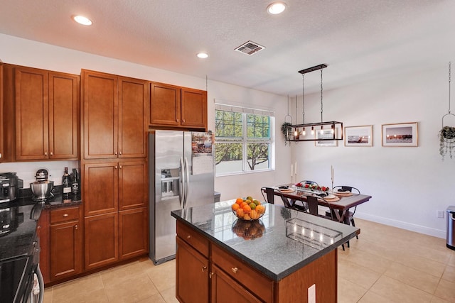 kitchen with stainless steel fridge with ice dispenser, brown cabinets, dark stone countertops, a center island, and recessed lighting