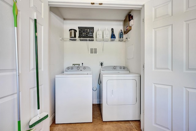 washroom featuring laundry area, visible vents, light tile patterned flooring, and washing machine and clothes dryer