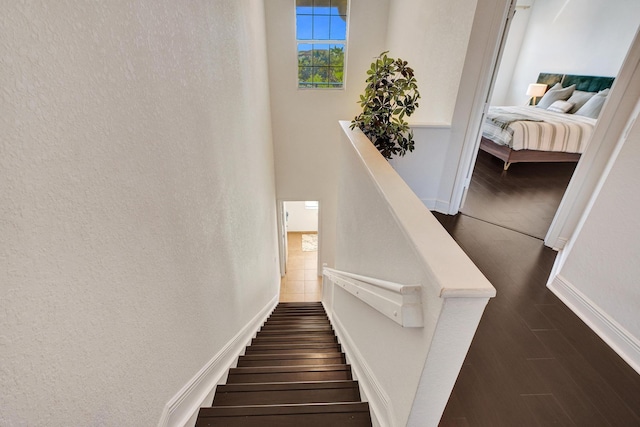 stairway with a textured wall, wood finished floors, and baseboards