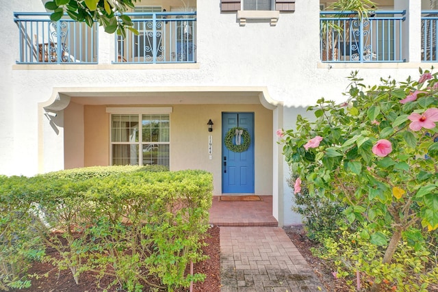 entrance to property with a balcony and stucco siding