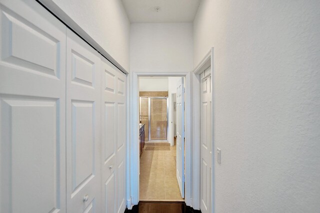 corridor featuring dark wood finished floors and a textured wall