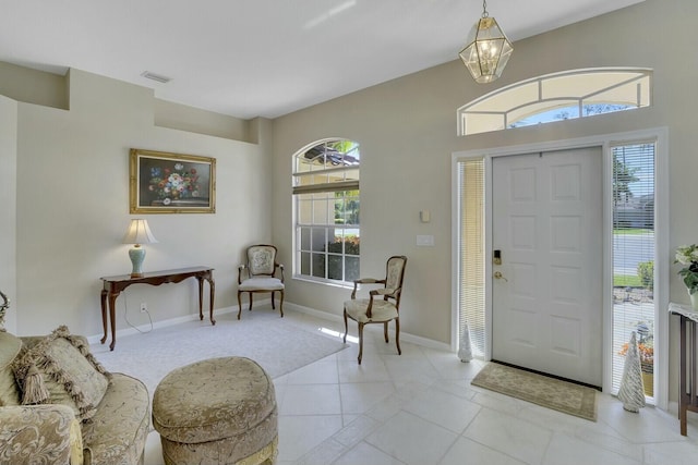 foyer entrance with a chandelier, visible vents, baseboards, and light tile patterned floors