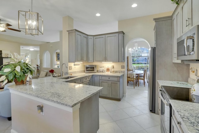 kitchen with stainless steel appliances, arched walkways, a sink, and gray cabinetry