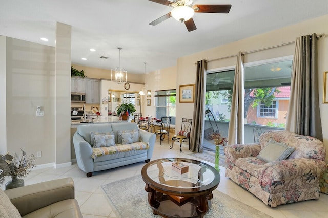 living area featuring recessed lighting, light tile patterned flooring, baseboards, and ceiling fan with notable chandelier