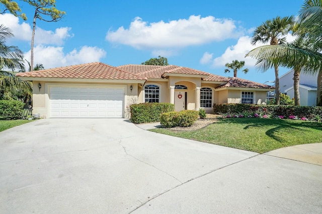 mediterranean / spanish-style home featuring an attached garage, a front lawn, concrete driveway, and stucco siding