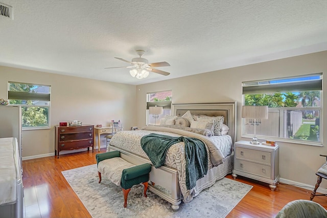 bedroom with multiple windows, baseboards, and wood finished floors