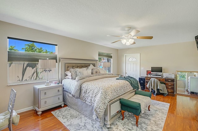 bedroom with ceiling fan, a textured ceiling, baseboards, and wood finished floors