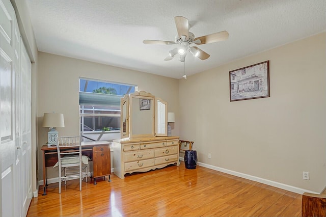 office area with baseboards, a textured ceiling, a ceiling fan, and light wood-style floors