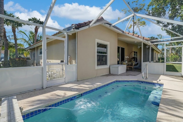 rear view of house with glass enclosure, a patio, a tiled roof, and stucco siding