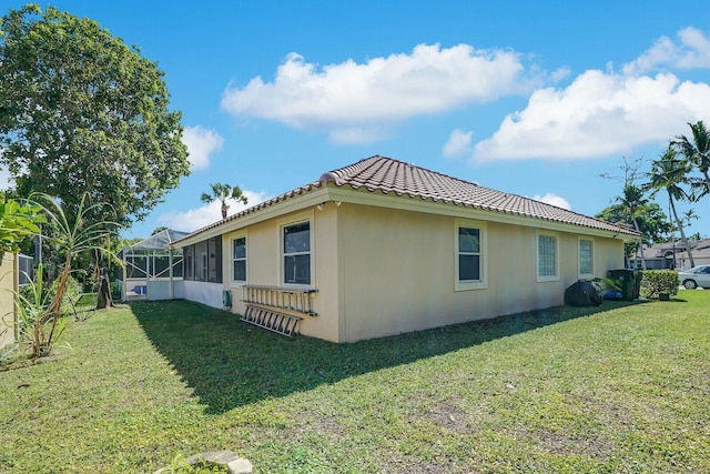 view of property exterior with a tile roof, glass enclosure, a yard, and stucco siding