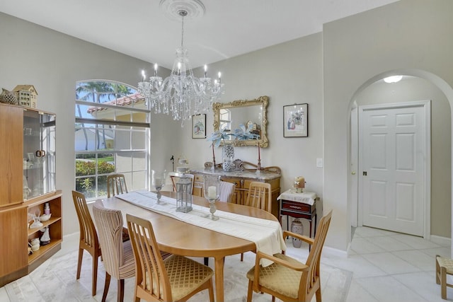 dining area featuring arched walkways, light tile patterned floors, a chandelier, and baseboards