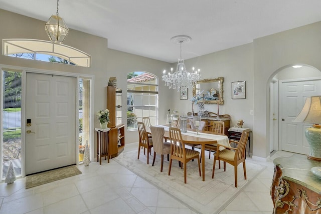 dining space featuring arched walkways, light tile patterned flooring, and an inviting chandelier