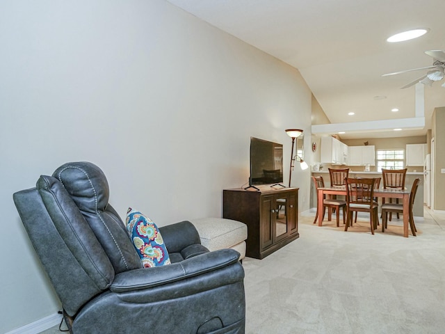 living room with light carpet, baseboards, lofted ceiling, and a ceiling fan