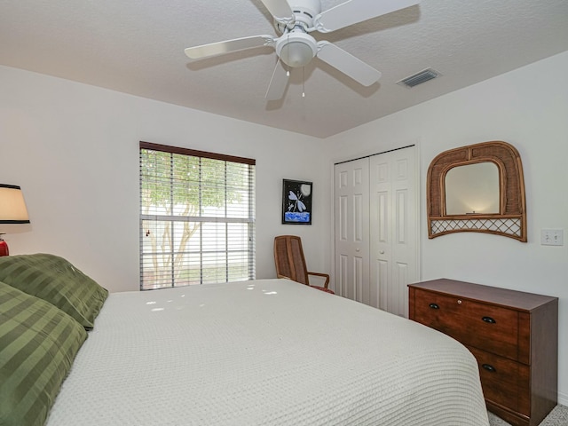 bedroom featuring a closet, visible vents, a textured ceiling, and ceiling fan