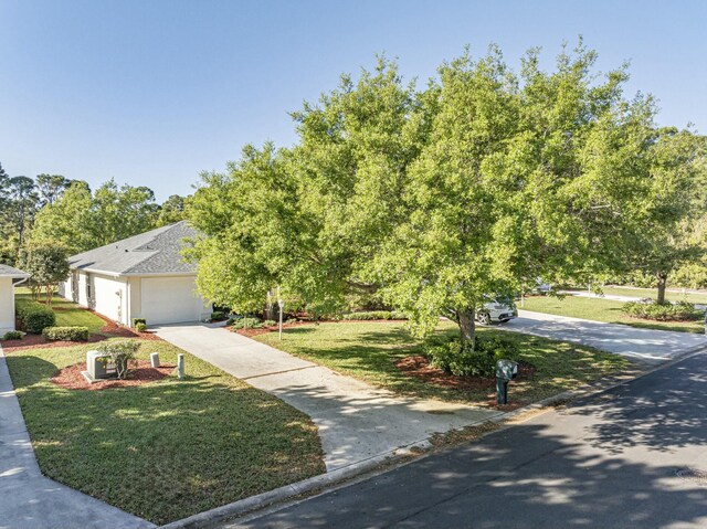 obstructed view of property with a garage, concrete driveway, and a front yard