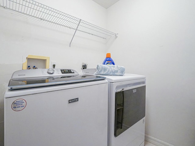 clothes washing area with laundry area, washer and dryer, and baseboards