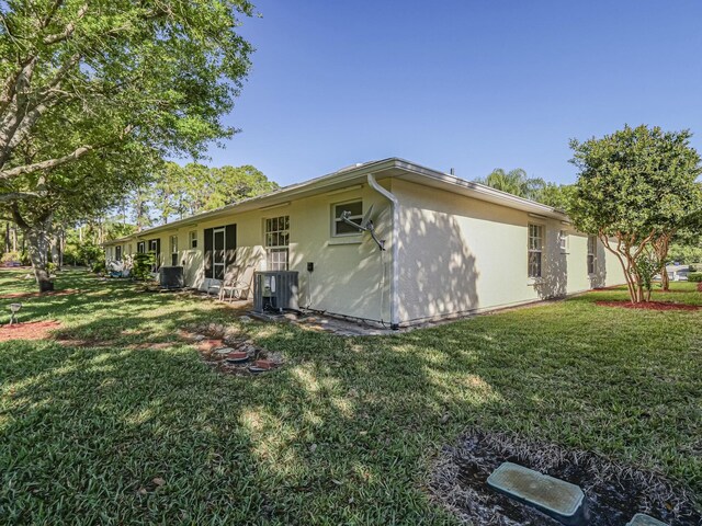 946 S Easy St, Sebastian, FL 32958 - rear view of property with central air condition unit, stucco siding, and a lawn