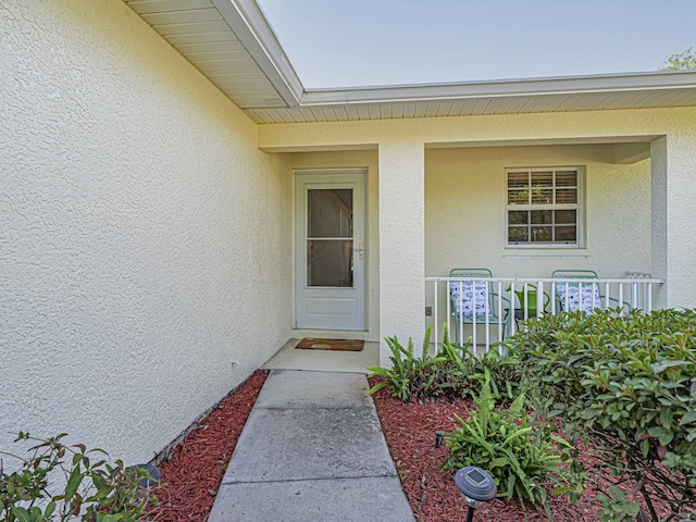 view of exterior entry featuring stucco siding and a porch