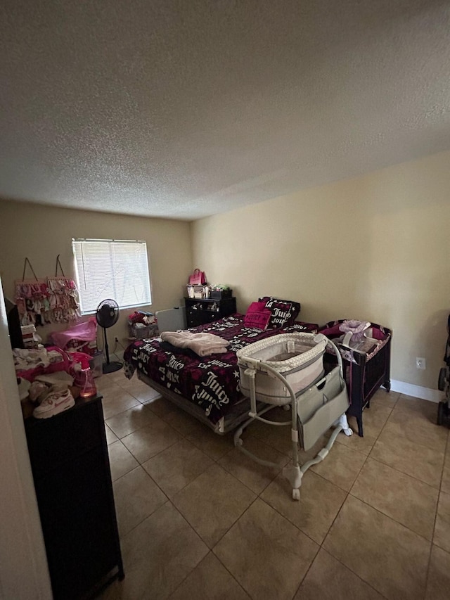 bedroom with baseboards, a textured ceiling, and light tile patterned flooring