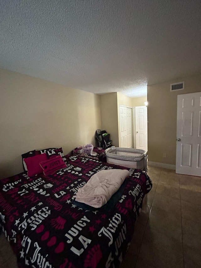 bedroom with visible vents, a textured ceiling, and light tile patterned flooring