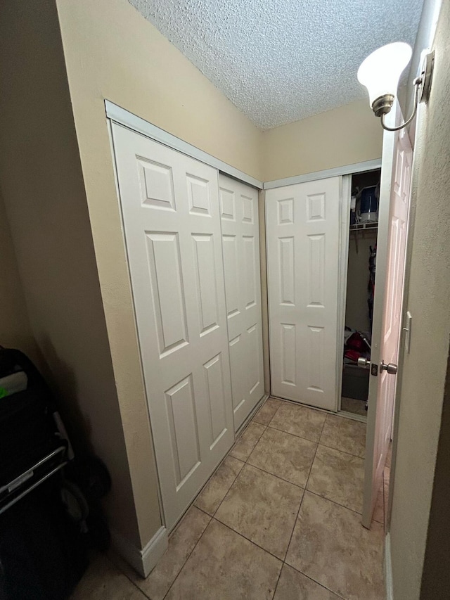 corridor with light tile patterned floors and a textured ceiling