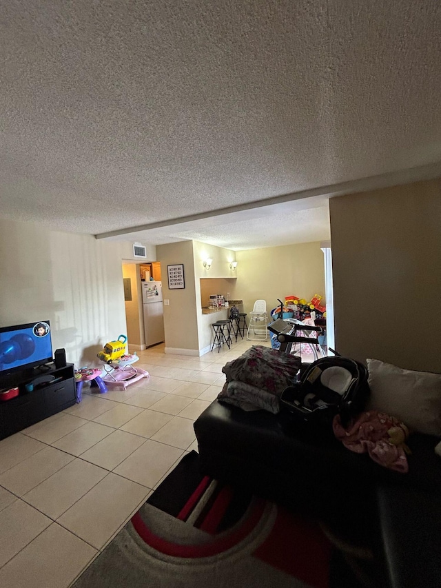 living area with visible vents, a textured ceiling, and light tile patterned floors