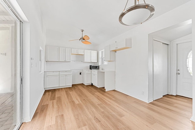 6560 Hayes St, Hollywood, FL 33024 - kitchen with a ceiling fan, white cabinetry, light wood-style floors, stainless steel microwave, and plenty of natural light