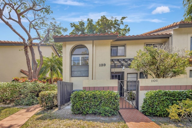 view of front of property with a tiled roof, a fenced front yard, a gate, and stucco siding