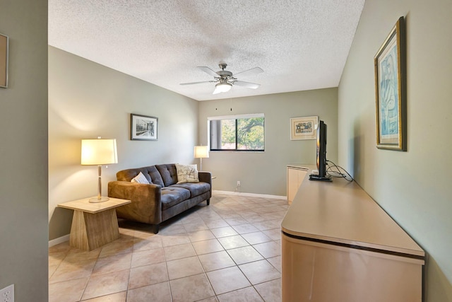 living area with a textured ceiling, light tile patterned flooring, a ceiling fan, and baseboards