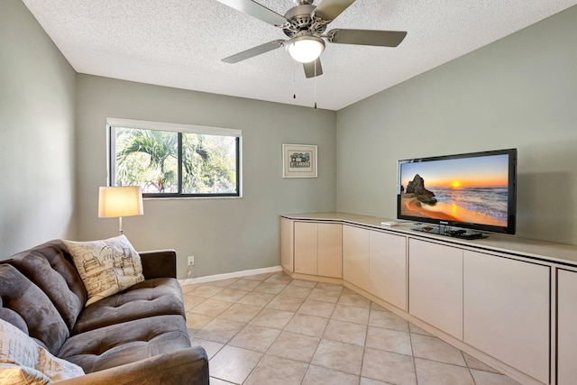 living room featuring baseboards, a ceiling fan, a textured ceiling, and light tile patterned flooring