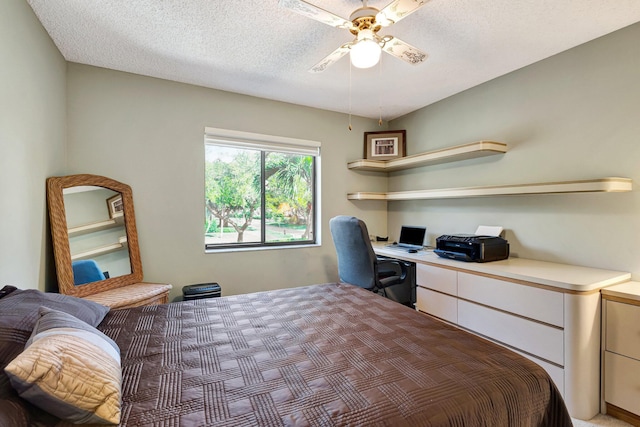 bedroom featuring a textured ceiling, ceiling fan, and built in desk