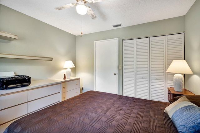 bedroom with a ceiling fan, a closet, visible vents, and a textured ceiling