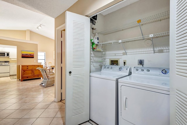 laundry room with light tile patterned floors, laundry area, a textured ceiling, and washing machine and clothes dryer