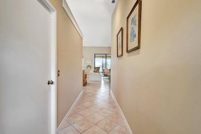 hall with light tile patterned floors, visible vents, and baseboards