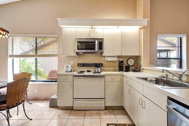 kitchen with stainless steel appliances, a healthy amount of sunlight, light tile patterned flooring, and a sink