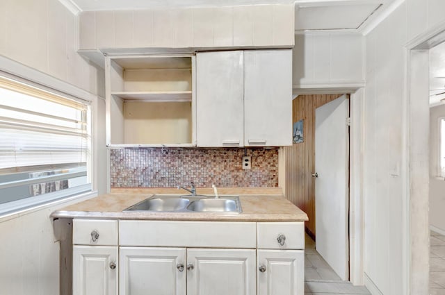 kitchen featuring tasteful backsplash, light countertops, a sink, and open shelves