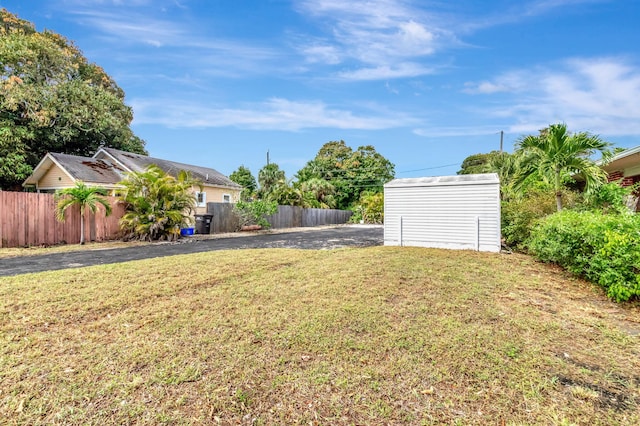 view of yard with an outbuilding, a storage shed, and fence