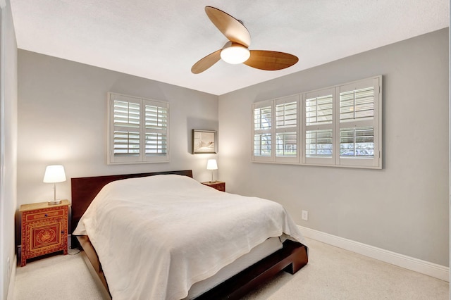 carpeted bedroom with ceiling fan and baseboards