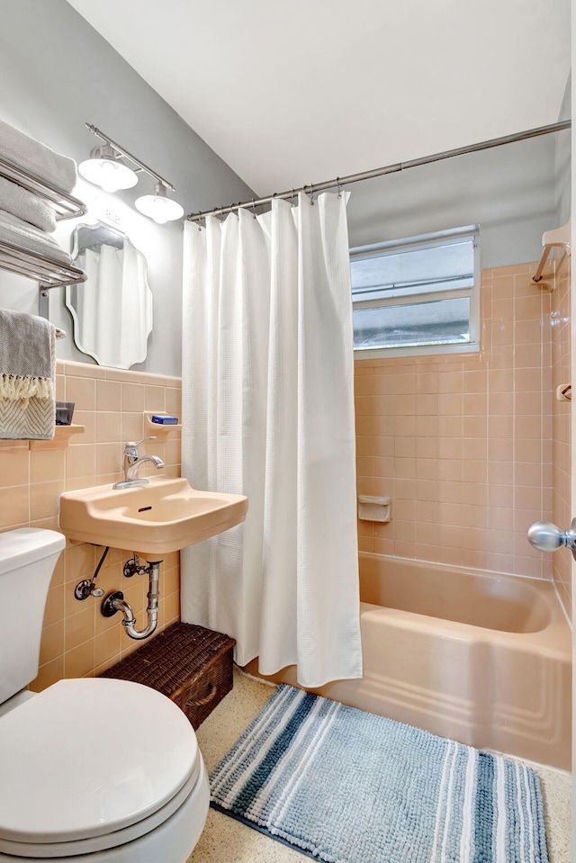 full bath with tile walls, toilet, shower / bath combo with shower curtain, wainscoting, and speckled floor