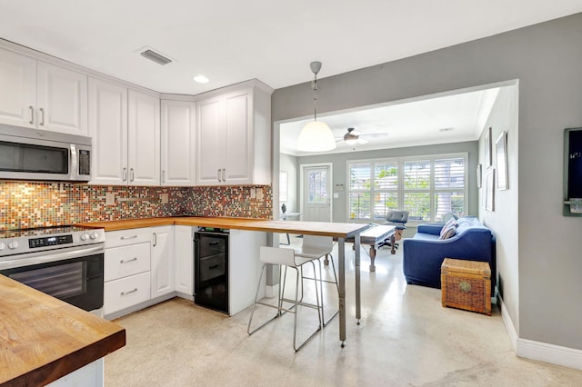 kitchen featuring stainless steel appliances, visible vents, backsplash, open floor plan, and butcher block countertops