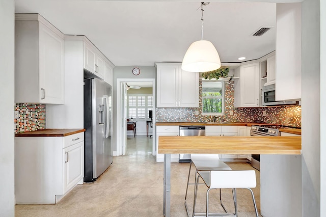 kitchen with stainless steel appliances, butcher block counters, visible vents, finished concrete flooring, and backsplash