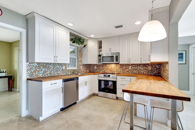 kitchen featuring butcher block countertops, appliances with stainless steel finishes, and tasteful backsplash