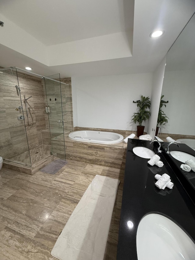 bathroom featuring a stall shower, a garden tub, a sink, and a tray ceiling