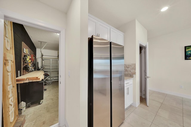 kitchen with baseboards, light tile patterned flooring, freestanding refrigerator, wood counters, and white cabinetry